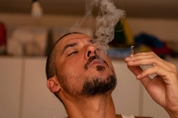 istock Man is Smoking Marijuana Cigarette Inside the House 1192276057