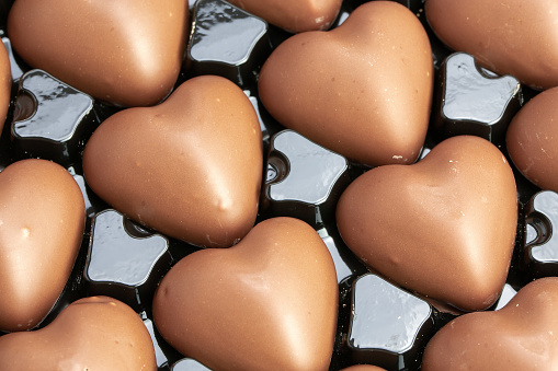 closeup of multitude of heart-shaped milk chocolate in their box