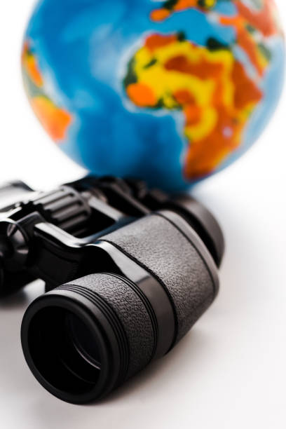 istock selective focus of black binoculars near globe on white 1192279405