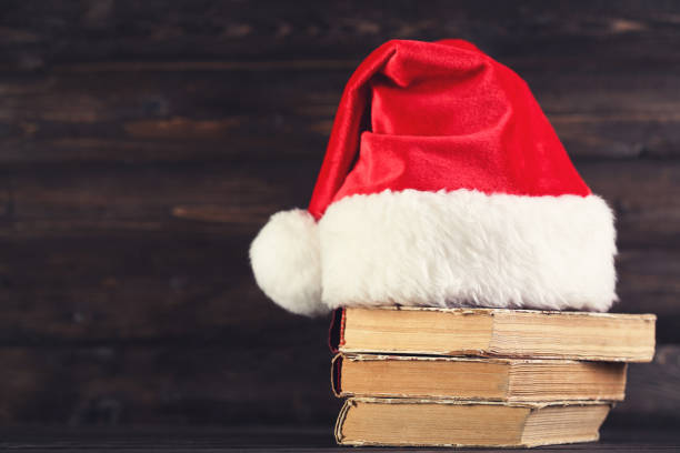 istock Red santa hat with stack of books on brown wooden background 1192280133