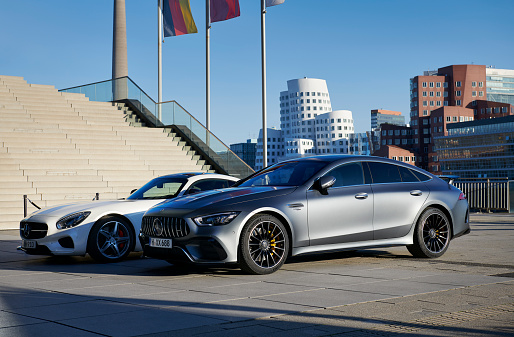 Duesseldorf, Germany - Dec 04, 2019: A gray Mercedes AMG GT 63s and a white Mercedes AMG GT S  at the Media Harbor, the Gehry buildings in the background.