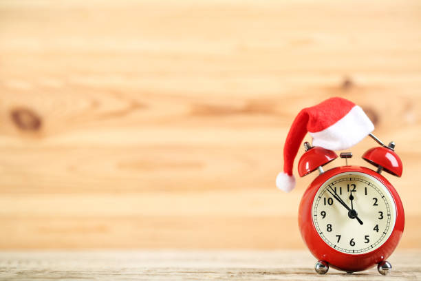 istock Red alarm clock with santa hat on brown wooden background 1192281904