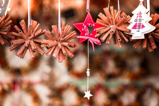 Close up color image depicting Christmas bauble decorations made from cinnamon sticks hanging in a row on a market stall at a Christmas market.