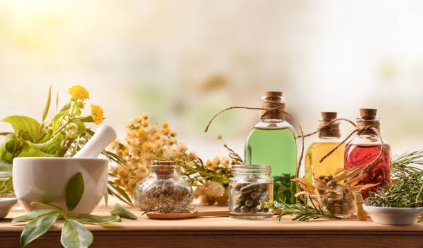 Composition of natural alternative medicine with capsules essence and plants Composition of natural alternative medicine with capsules, essence and plants on wooden table in rustic kitchen. Front view. Horizontal composition. herb stock pictures, royalty-free photos & images