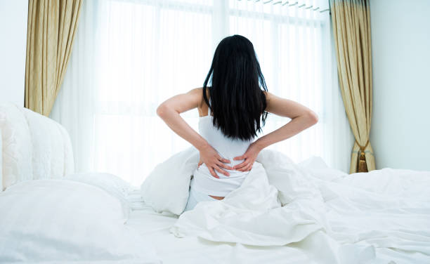 istock Young lady waking up and sitting in bed with hands raised 1192288393