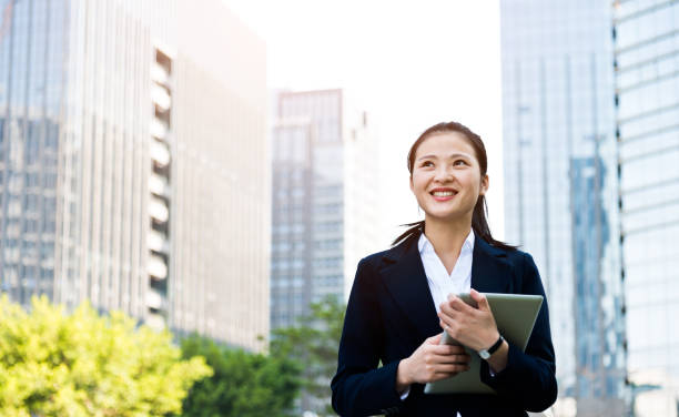 istock Asian businesswoman using digital tablet outside offic building 1192289849