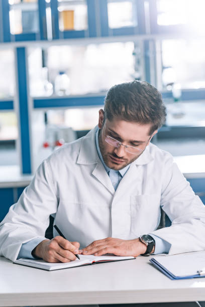 istock handsome allergist writing in notebook near clipboard on table 1192290779