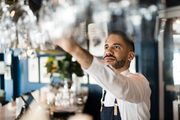 Bartender arranging wine glasses Young bartender with beard arranging food and drink establishment stock pictures, royalty-free photos & images