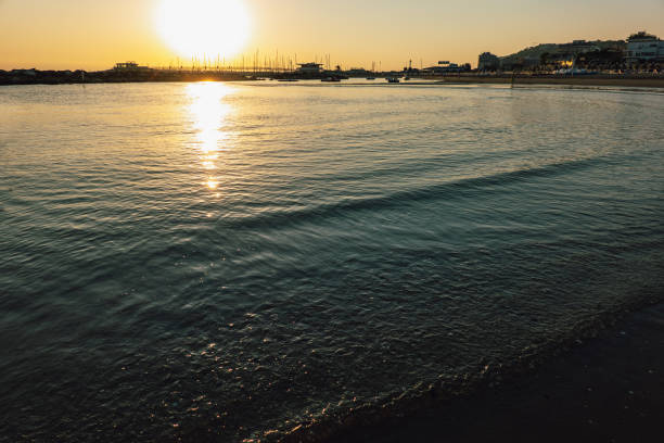 istock Waves on Sandy Beach Background at Sunrise or Sunset with Harbour 1192295814
