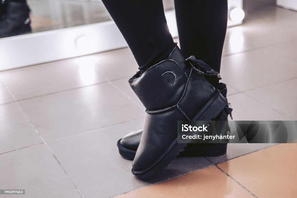 The girl in the mall measures boots made of genuine leather. Ugg Boot Stock Photo