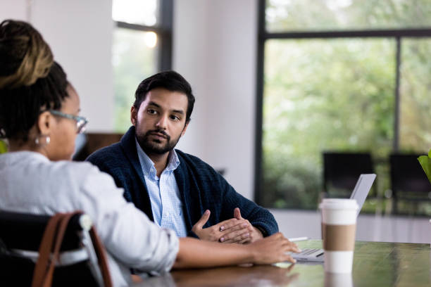 Mid adult manager meets with male employee for progress report The unrecognizable mid adult female manager meets with her mid adult employee for a monthly progress report. serious talk stock pictures, royalty-free photos & images