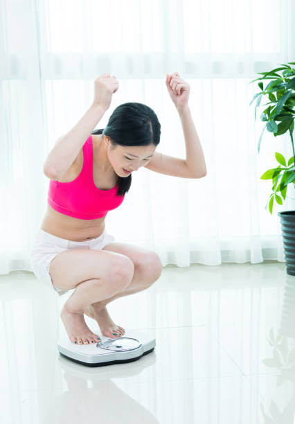 istock Happy woman crouching on a weighing scale. 1192299861