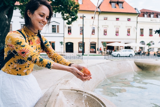 Hungry tourist woman rinsing an apple outside at summer travel in Slovakia