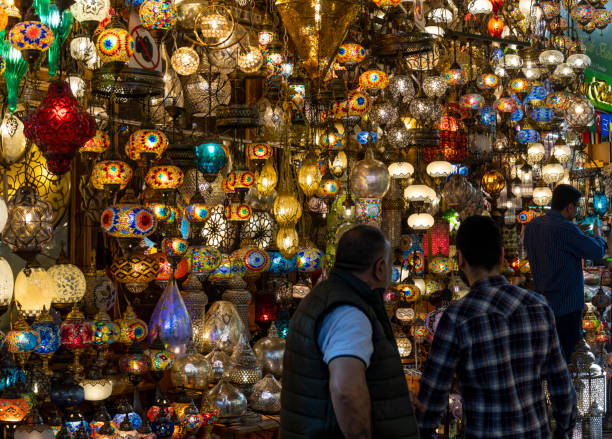 Istanbul, Turkey - April 29, 2019: Lamp shop in the great bazaar in Instanbul with colored lamps packed in the shop and two men.