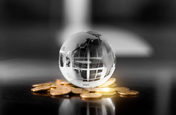 globe de cristal sur des piles de pièces de monnaie - currency exchange globe currency global business photos et images de collection