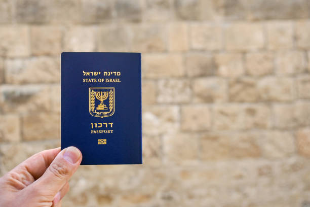 Male hand holds an Israel passport with ancient wall of old Jaffa stock photo