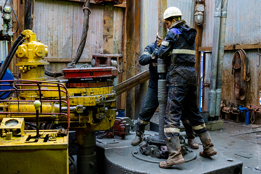 Trabajador de plataformas petrolíferas en alta mar prepara herramientas y equipos para perforación de petróleo y gas bien en la plataforma de cabezal de pozo. Haciendo una conexión de tubería de perforación. Una vista para la conexión de tubos de pe photo