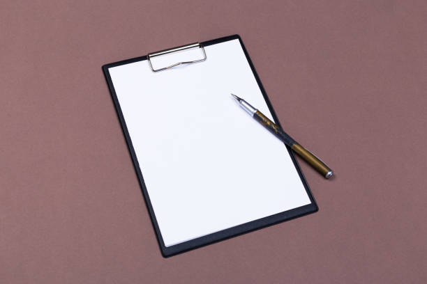 istock Clipboard with white sheet and pen on a colored background. View from above. space for text 1192307064