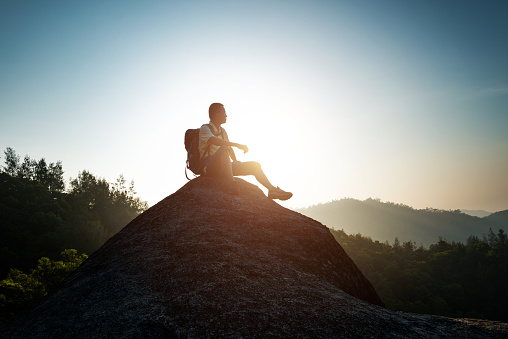 Male backpacker sitting on ledge of mountains