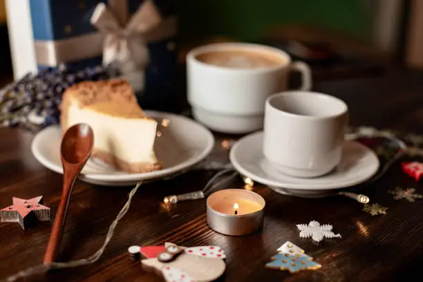 Christmas coffee with candle and cake on brown wooden table