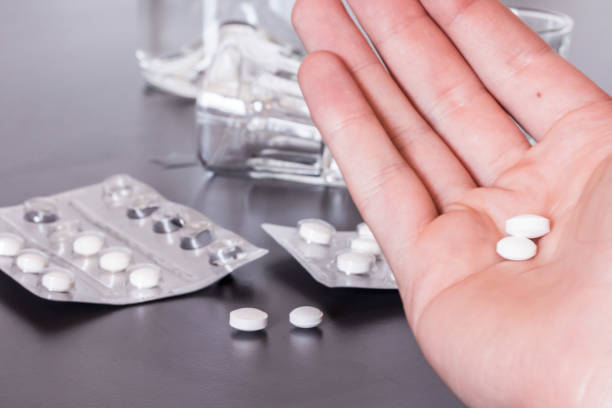istock Drug abuse: Close up of pills and alcohol on a grey table 1192308243