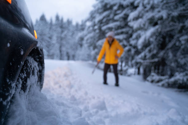 istock Cleaning the car and sweeping after the first snow. Emergency lights. Car issues in the middle of nowhere in bad weather. Car insurance. One woman on the road. 1192308404