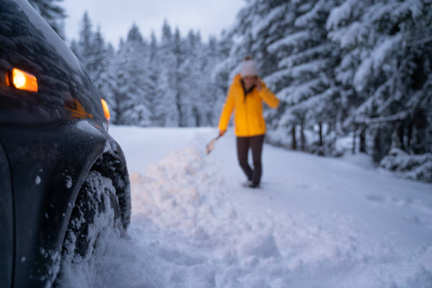 istock Cleaning the car and sweeping after the first snow. Emergency lights. Car issues in the middle of nowhere in bad weather. Car insurance. One woman on the road. 1192308438