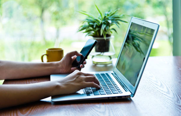 istock Woman using phone and laptop in a coffee shop 1192309809