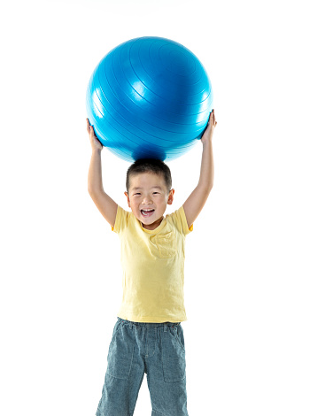 Little boy playing with a ball against white background.