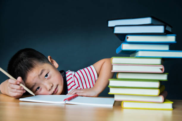 istock Little asian boy with stack of books 1192310978