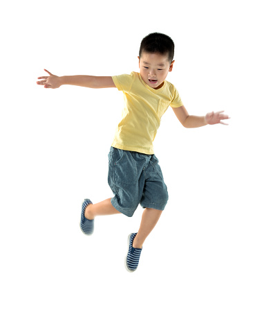 Happy schoolboy with backpack jumping on grey background