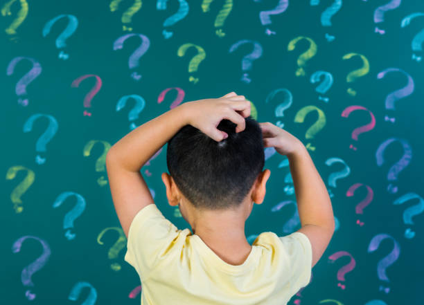 istock Asian boy in front of blackboard with question marks 1192311858