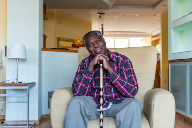 Senior Afro-American is Relaxing in Armchair at Home Senior Afro-American with Walking Stick is Sitting in Comfortable Armchair in the Living Room at Home. alzheimer patient stock pictures, royalty-free photos & images