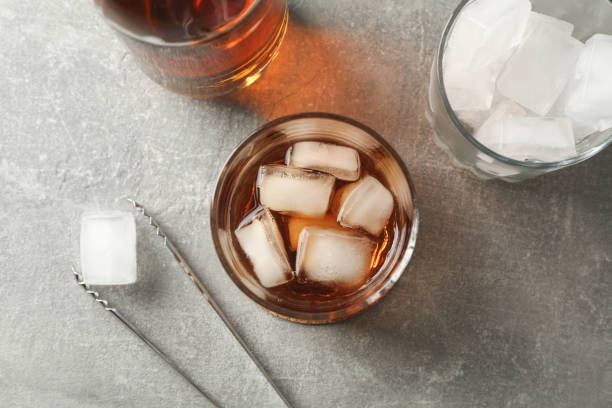 istock Bottle, glasses with ice cubes and whiskey on grey background, top view 1192313388