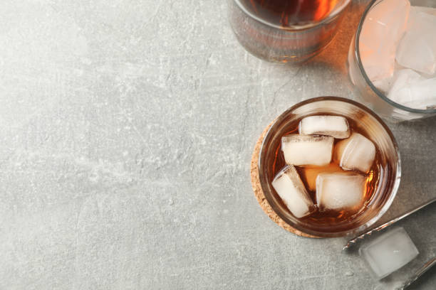 istock Bottle, glasses with ice cubes and whiskey on grey background, top view 1192313724