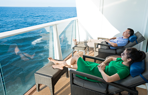Young couple relaxing in balcony with scenic sea views on a cruise ship.