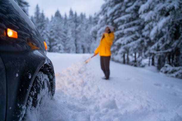 istock Cleaning the car and sweeping after the first snow. Emergency lights. Car issues in the middle of nowhere in bad weather. Car insurance. One woman on the road. 1192316802