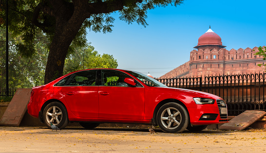 Delh/India-October16,2019. A red AUDI Sedan car parking overlooking the Famous Historical  Delhi Red Fort.