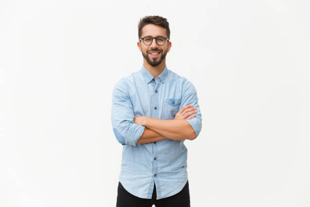 Happy laughing guy posing with arms folded Happy laughing guy posing with arms folded. Handsome young man in casual shirt and glasses standing isolated over white background. Male portrait concept shirt photos stock pictures, royalty-free photos & images