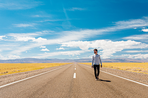 Young man walking on empty road