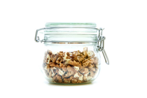 The walnuts stored inside the closable glass bottle isolated on a white background.