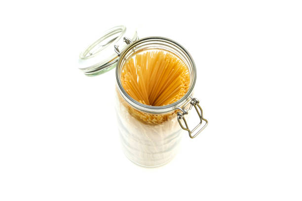 The spaghetti pasta stored inside the closable glass bottle isolated on a white background.