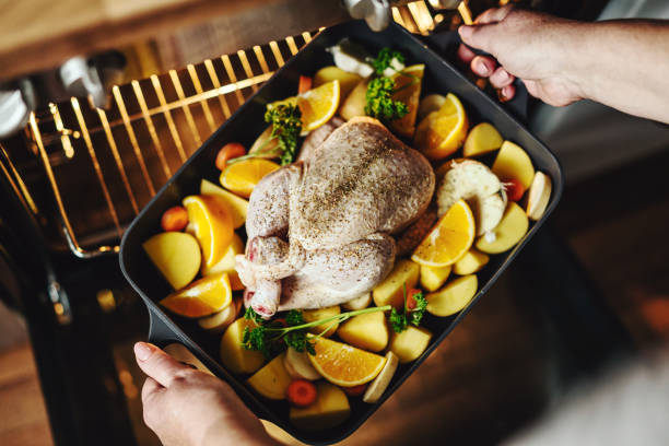 istock Woman puting raw chicken with vegetables in oven. Closeup 1192342302
