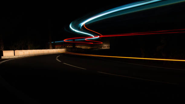 Long exposure of sweeping lights of traffic on a winding road Long exposure of red orange and blue sweeping lights from the traffic on a winding road in the mountains of Tenerife. Showing motion and movement forward in an abstract way with copy space. sweeping photos stock pictures, royalty-free photos & images
