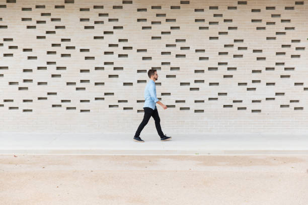 Side view of Caucasian guy moving by contemporary brick wall