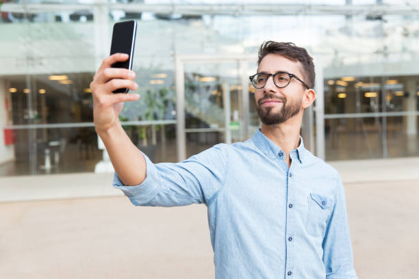 istock Positive smiling guy in eyewear with mobile phone taking selfie 1192352758