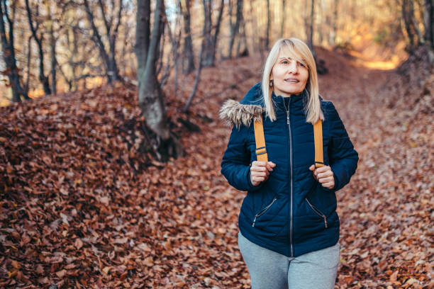 istock Mature female  with backpack walking in forest at autumn 1192355610