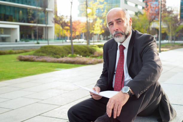 istock Businessman with papers sitting on street 1192361689