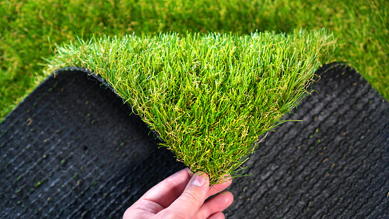 Mano sosteniendo un rollo de hierba artificial. Greenering con un césped artificial. photo