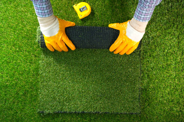Men's hands hold a roll of artificial grass. Artificial turf background. Men's hands hold a roll of artificial grass. Artificial turf background. artificial stock pictures, royalty-free photos & images